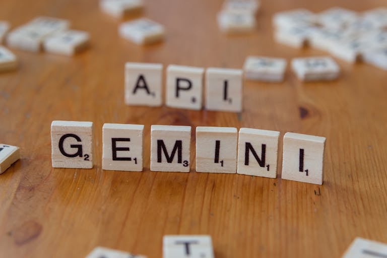 Close-up of Scrabble tiles forming the words 'API' and 'GEMINI' on a wooden surface.